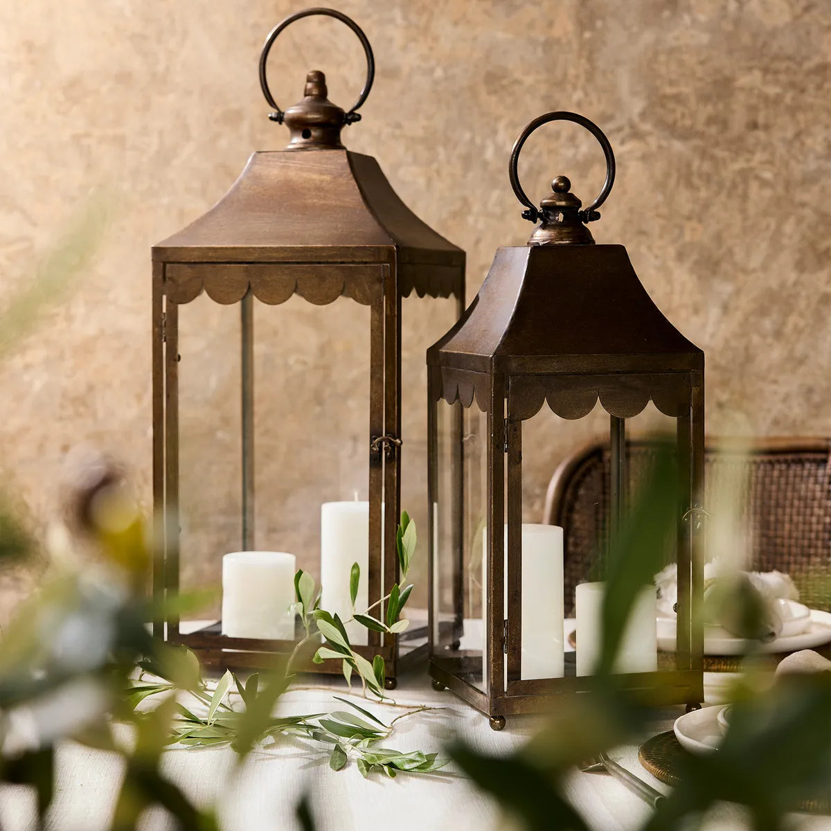 Two vintage style lanterns with candles inside on a table with a blurred background