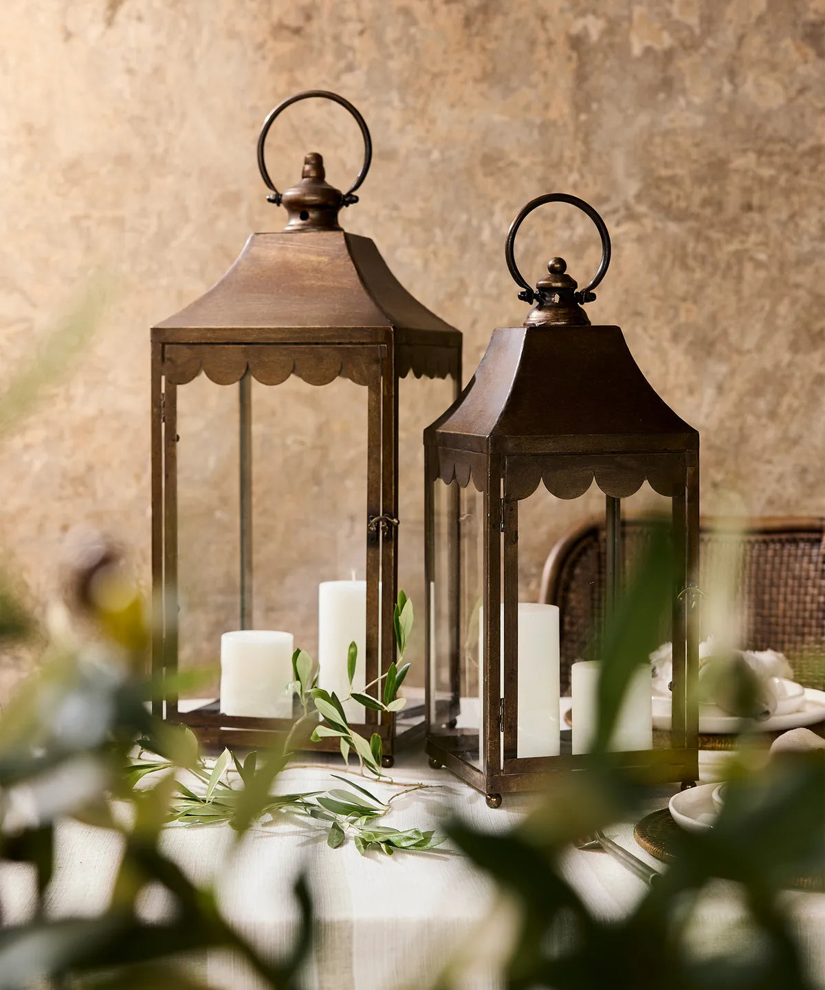 Two vintage style lanterns with candles inside on a table with a blurred background