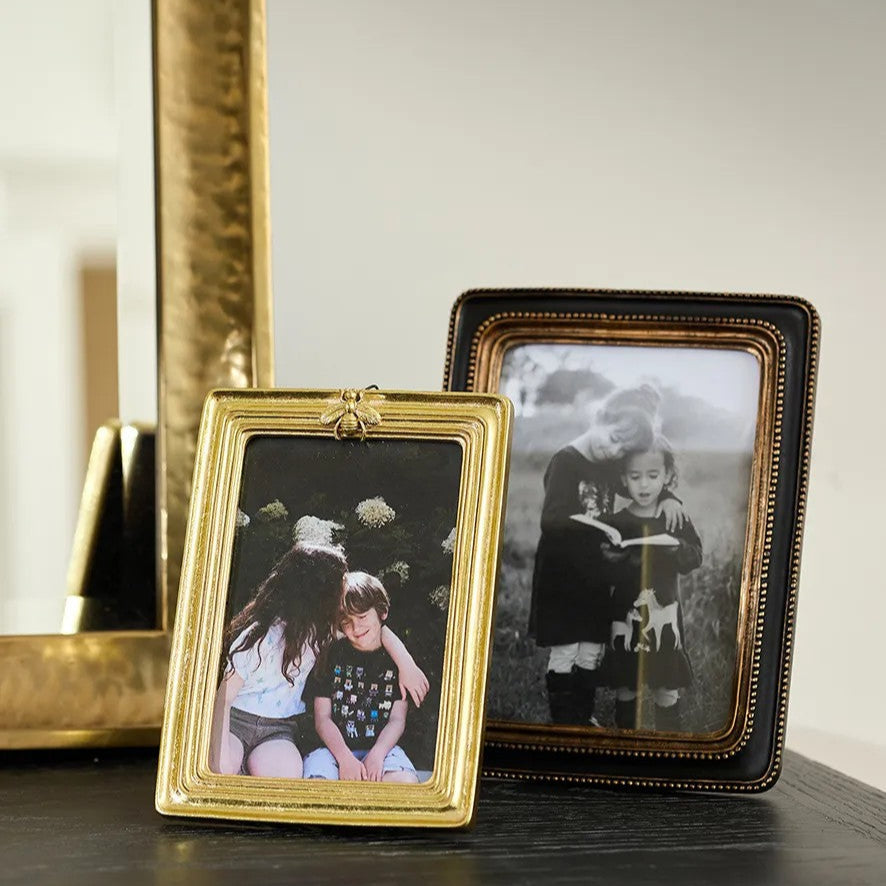 Gold Bee photo frame and black  with gold beaded photo frame on console