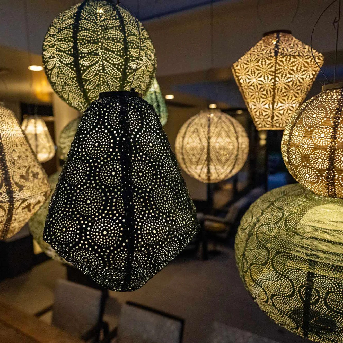 NIght shot of hanging green lantern with other lanterns in the back ground showing light play