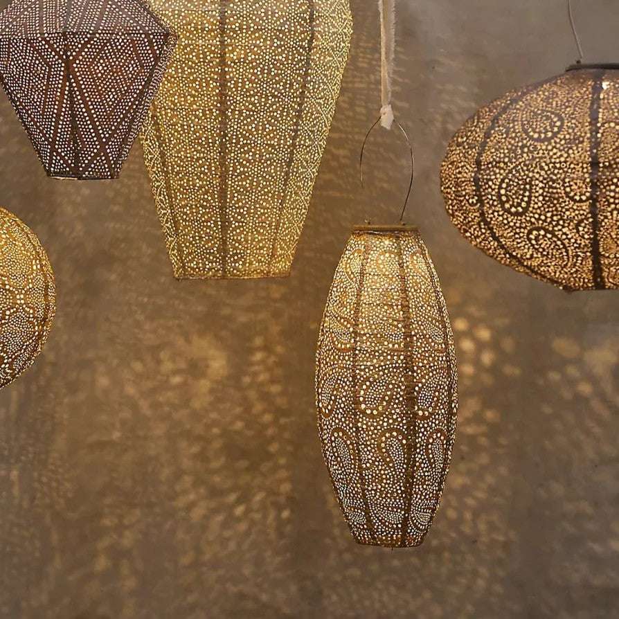 Group shot of hanging lanterns in different shapes at night time showing glow