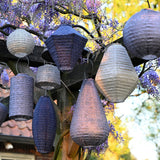 Many decorative solar lanterns hanging from a tree in several shapes and colours