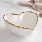 Heart shaped white porcelain bowl with gold trim on edges.