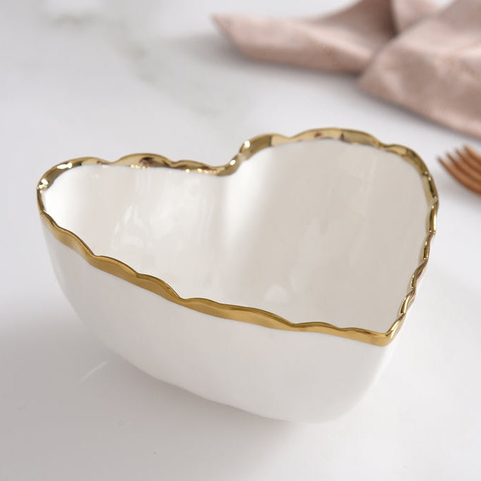 Heart shaped white porcelain bowl with gold trim on edges.