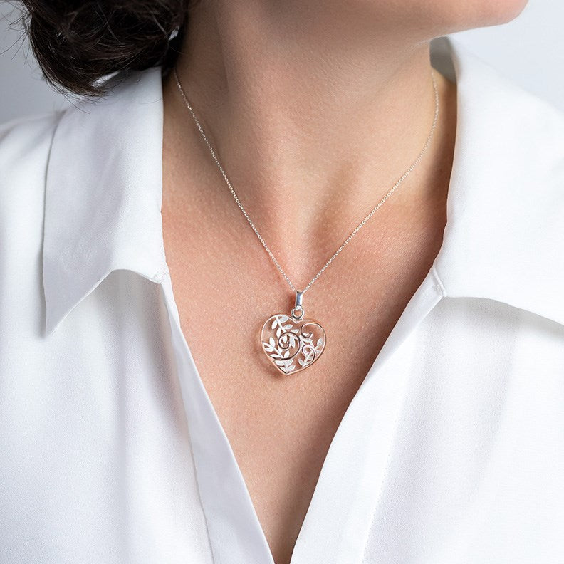Model Wearing Silver Necklace with Heart shaped Pendant featuring the NZ Fern and Koru  with Rose gold plating. Comes with a 40 - 45m Sterling Silver Chain.