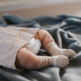 Baby wearing Lamington Merino Wool Baby Socks at Cerise in Ted design featuring white crosses on oatmeal base.