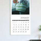 Calendar with a decorative illustration of a person holding flowers on a light gray wall.