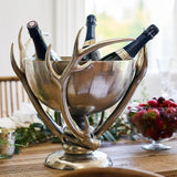 Decorative wine cooler with antler design on a table with bottles inside