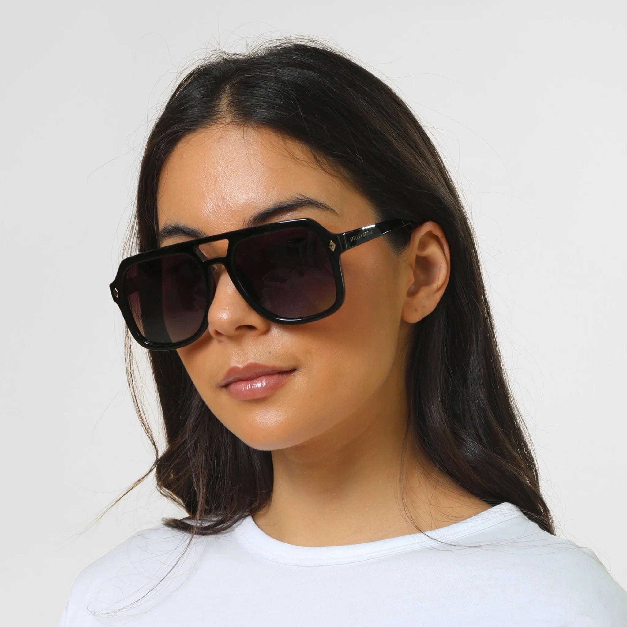 Woman wearing dark sunglasses against a plain background