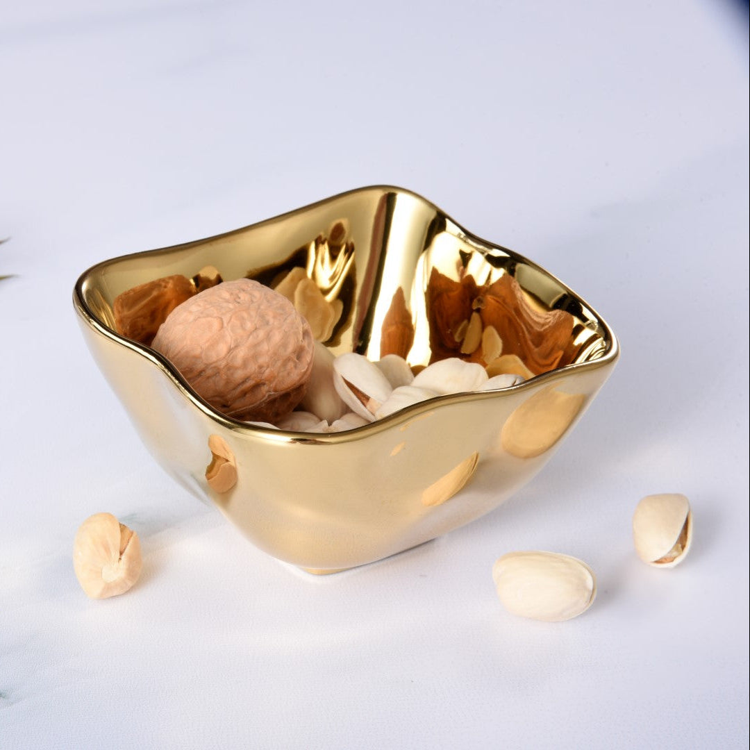Gold decorative bowl with nuts on a light background