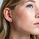 A woman wearing silver studs featuring a hummingbird