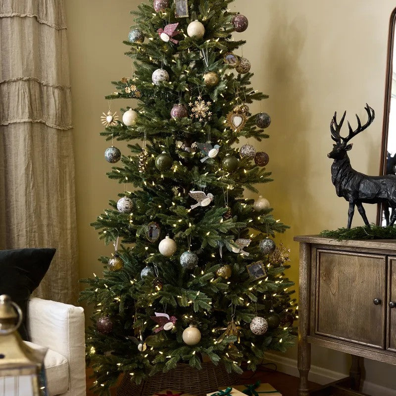 Decorated Christmas tree with ornaments and lights in a living room setting.