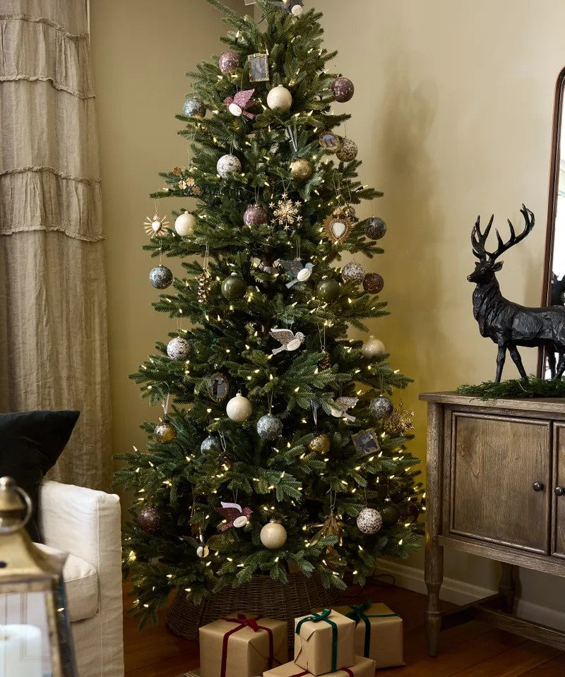 Decorated Christmas tree with ornaments and lights in a living room setting.