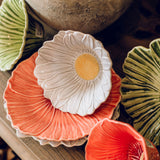White daisy with yellow centre ceramic bowl diplayed with other colourful plates