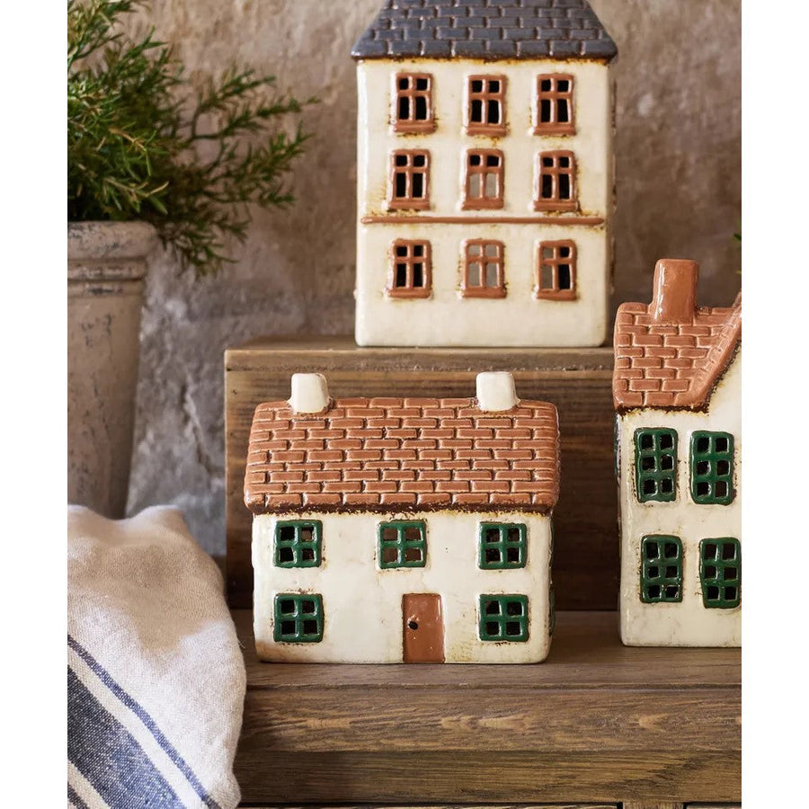Set of miniature ceramic houses on a wooden surface with a neutral background