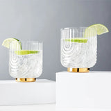 These 1920"s style elegant glasses feature a draping style glass offering a striking silhouette with polished gold plated base. Perfect for whiskey, margarita, negroni and more.  Boxed set of 2 Belmont Gatsby 12 oz Glasses.  High quality glass with gold electroplating.  Handwash only.